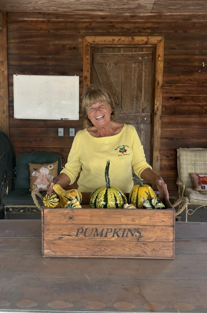 Bernie behind a wooden crate of pumpkins and squash